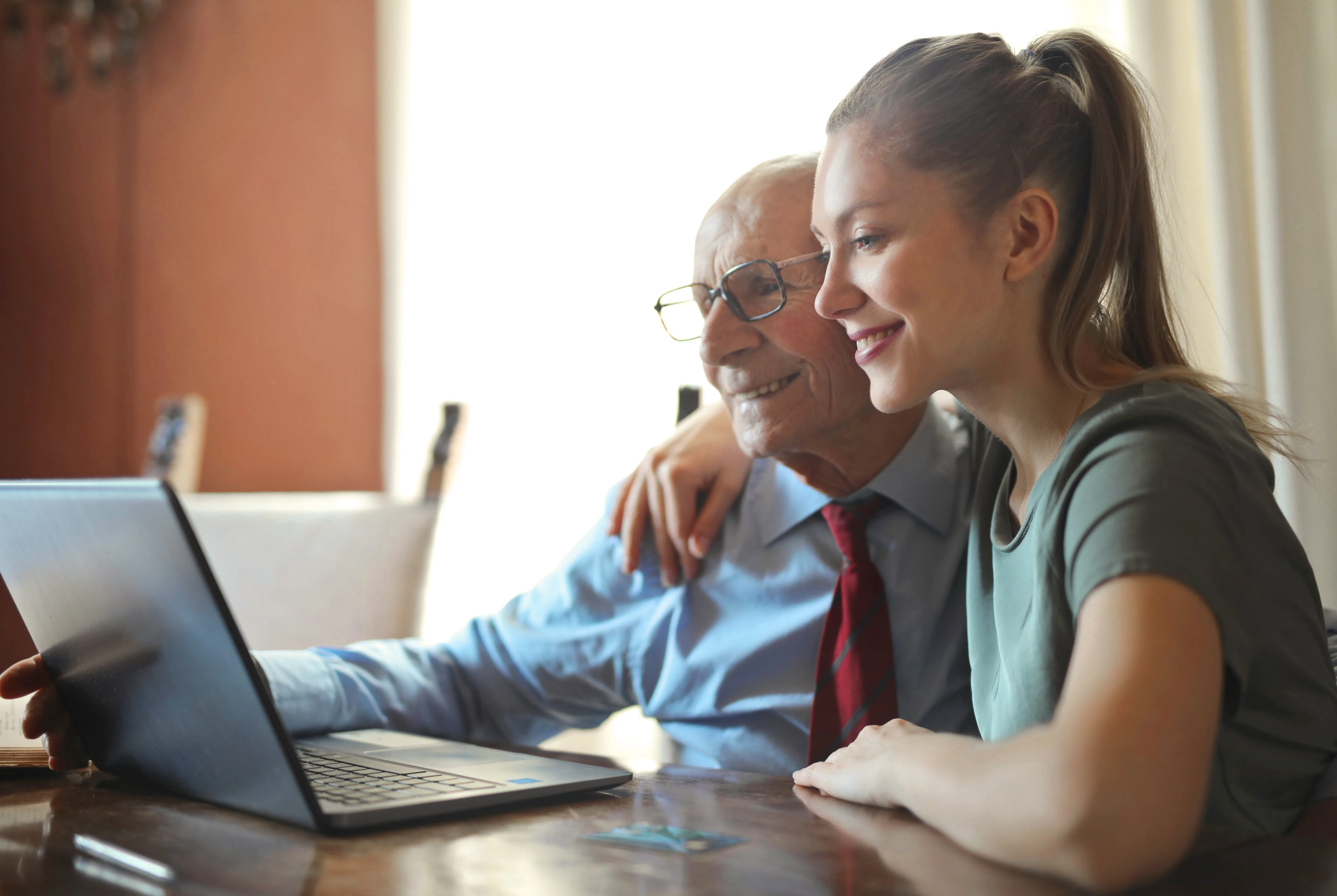 A granddaughter and grandfather together looking at a screen and smiling